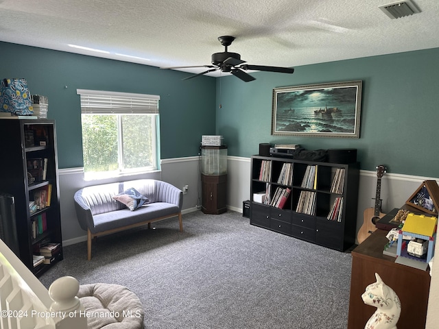 sitting room featuring ceiling fan, carpet floors, and a textured ceiling