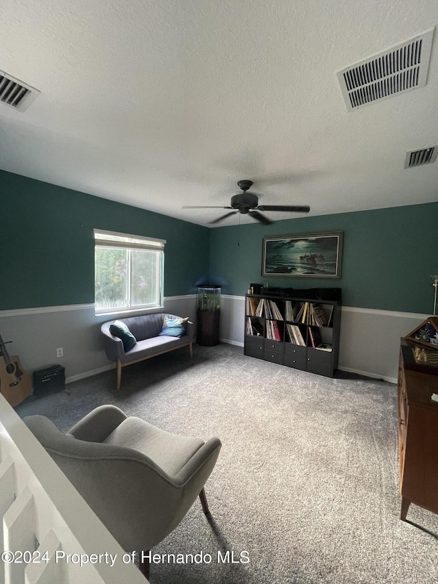 carpeted living room with ceiling fan and a textured ceiling