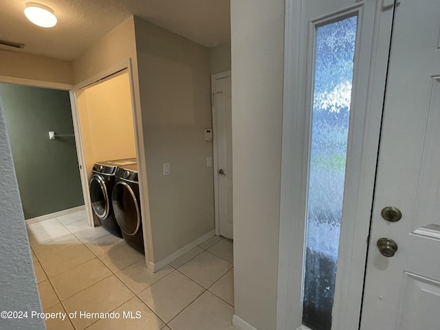 washroom featuring light tile patterned flooring, a textured ceiling, and washer and clothes dryer