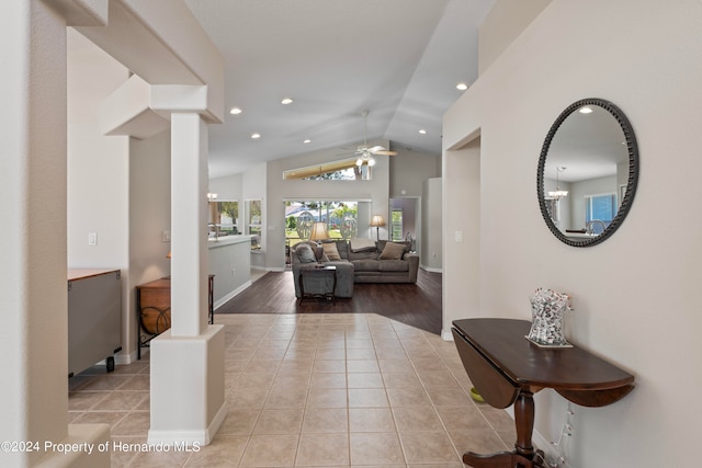 hall with light hardwood / wood-style floors, lofted ceiling, and an inviting chandelier