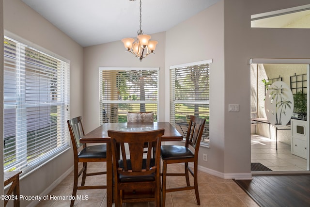 tiled dining room with lofted ceiling and an inviting chandelier