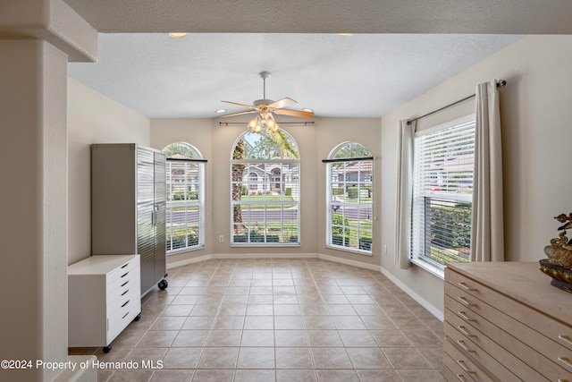 unfurnished dining area featuring ceiling fan, a textured ceiling, and light tile patterned floors