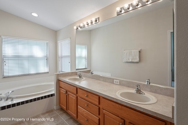 bathroom with vanity, a relaxing tiled tub, tile patterned floors, and vaulted ceiling