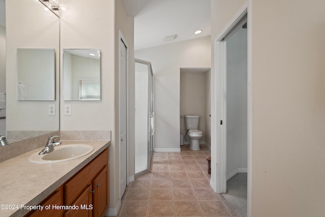 bathroom with toilet, lofted ceiling, tile patterned floors, and vanity