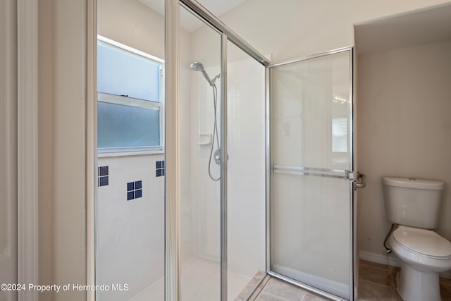 bathroom with an enclosed shower, tile patterned floors, and toilet