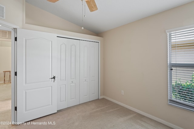 unfurnished bedroom with a closet, multiple windows, vaulted ceiling, and ceiling fan