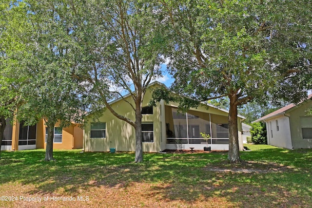 rear view of house featuring a lawn and a sunroom