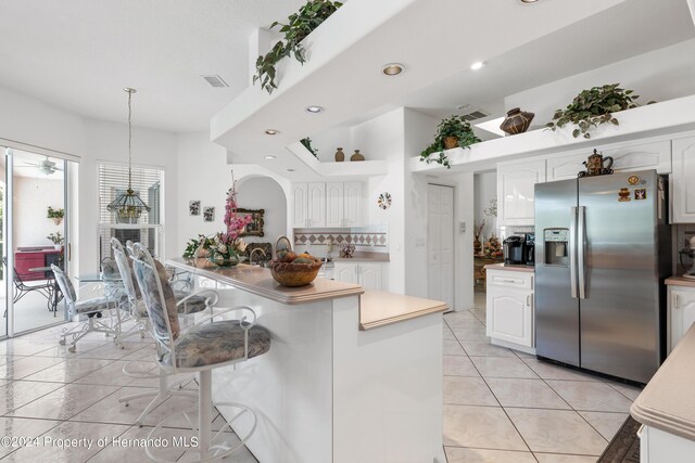 21312 Preservation Dr, Land O Lakes, FL 34638 - kitchen with white cabinetry, a breakfast bar area, stainless steel fridge, light tile patterned floors, and visible vents