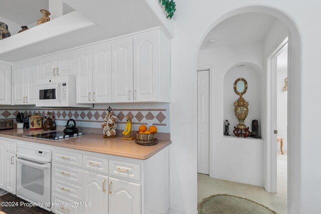 21312 Preservation Dr, Land O Lakes, FL 34638 - kitchen with white cabinetry, arched walkways, tasteful backsplash, and white appliances