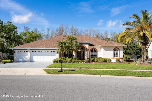 21312 Preservation Dr, Land O Lakes, FL 34638 - view of front of home with stucco siding, roof with shingles, driveway, a front yard, and a garage