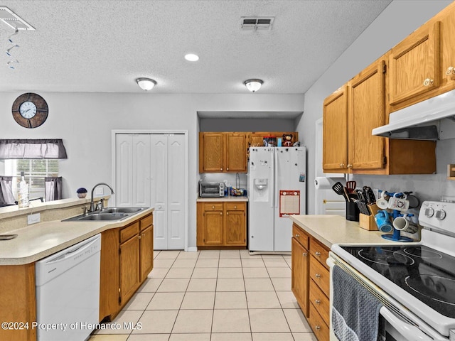 kitchen featuring a textured ceiling, sink, white appliances, and light tile patterned floors