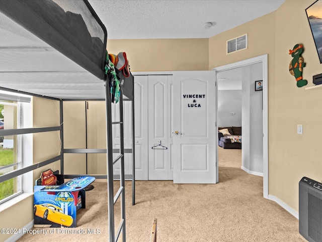 bedroom with a textured ceiling, light carpet, and a closet