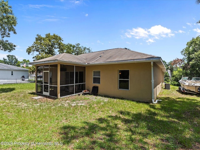 back of property featuring central AC unit, a sunroom, and a yard