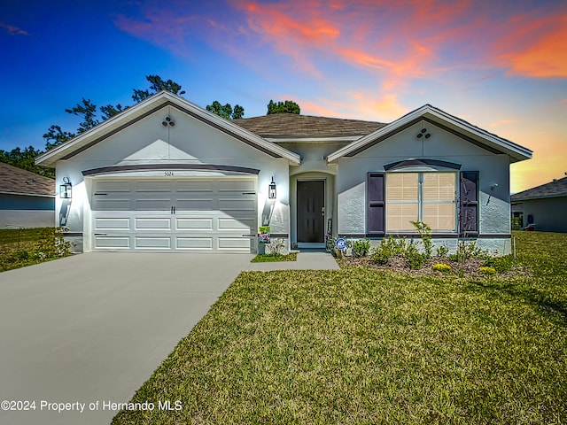 ranch-style home featuring a garage and a yard