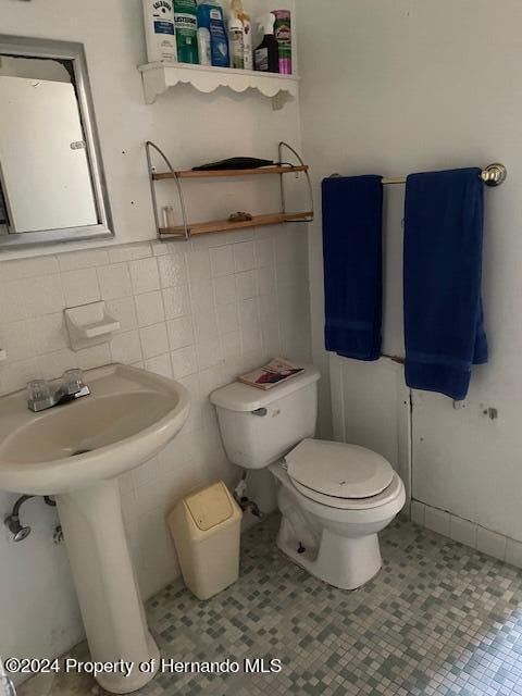 bathroom featuring tile walls, sink, and toilet