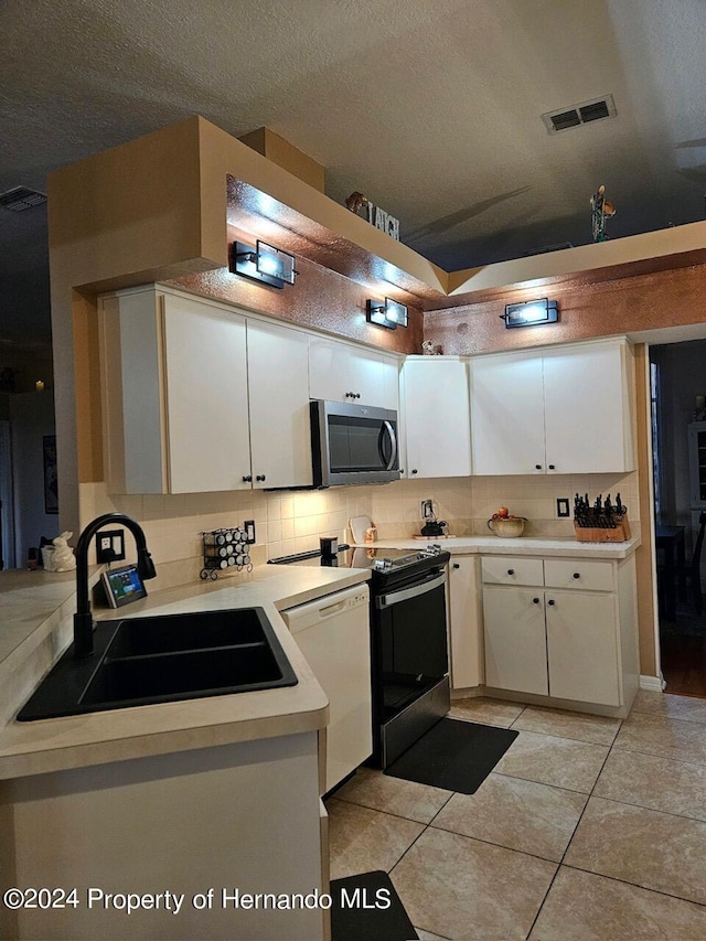 kitchen with light tile patterned flooring, a textured ceiling, white dishwasher, sink, and white cabinets