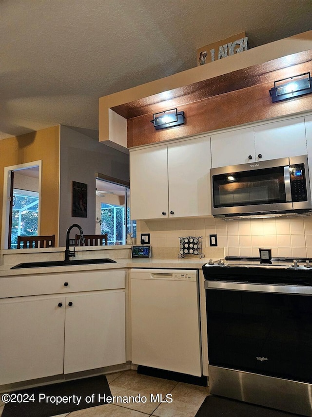 kitchen featuring light tile patterned flooring, stainless steel appliances, white cabinetry, sink, and decorative backsplash