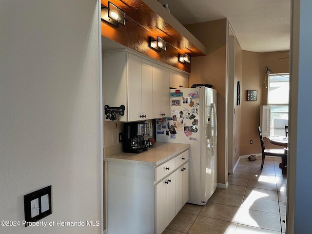 kitchen with backsplash, white cabinetry, light tile patterned floors, and white fridge