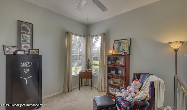 living area with ceiling fan, light colored carpet, and a healthy amount of sunlight