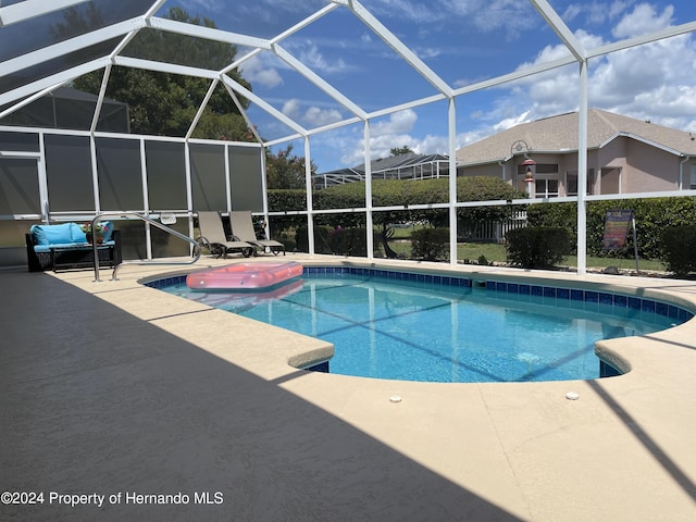 view of pool featuring glass enclosure and a patio area