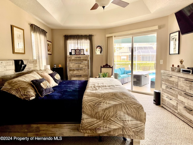 bedroom with access to outside, light colored carpet, ceiling fan, and a raised ceiling