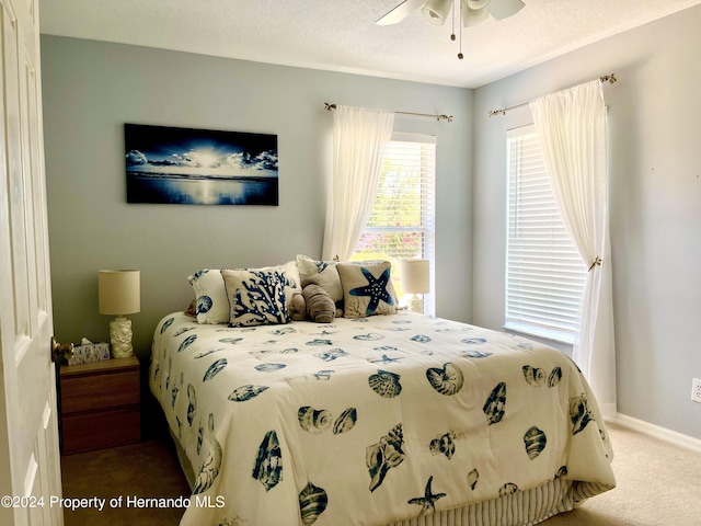 carpeted bedroom with ceiling fan and a textured ceiling