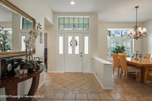 tiled foyer featuring a notable chandelier and a textured ceiling