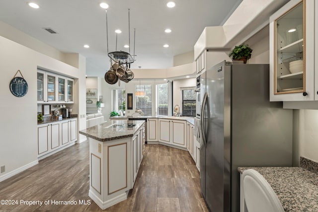 kitchen with hardwood / wood-style flooring, stainless steel refrigerator, stone countertops, a center island, and cream cabinetry