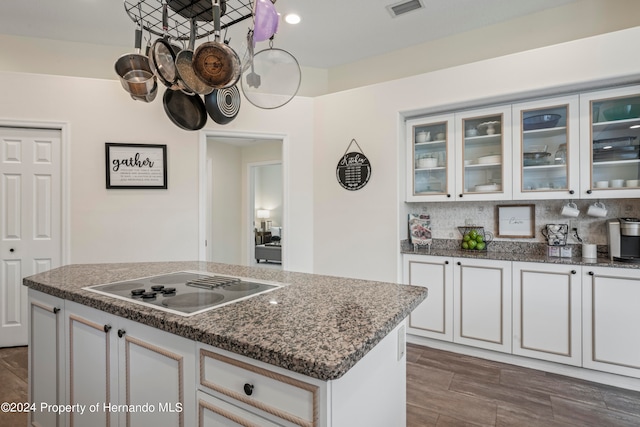 kitchen featuring a kitchen island, white electric stovetop, decorative backsplash, and white cabinets