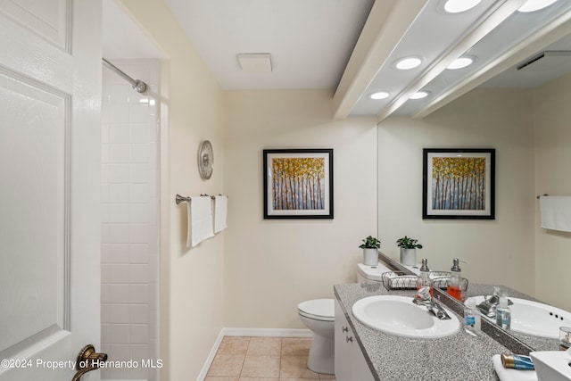 bathroom with toilet, vanity, tile patterned flooring, and tiled shower