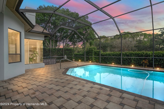 pool at dusk featuring a patio area and a lanai