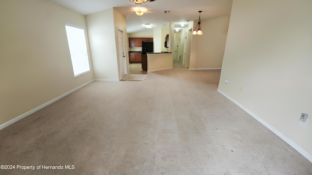 unfurnished living room with ceiling fan with notable chandelier, light carpet, and vaulted ceiling