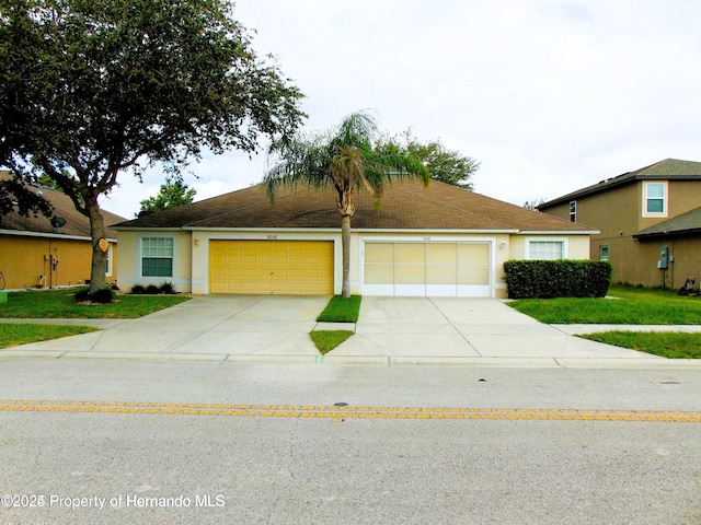 ranch-style house featuring a garage, driveway, and stucco siding