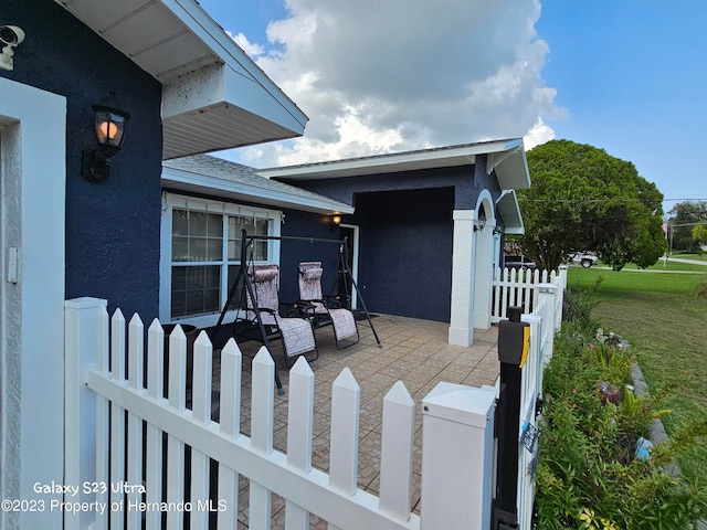 view of exterior entry with a lawn and a patio area