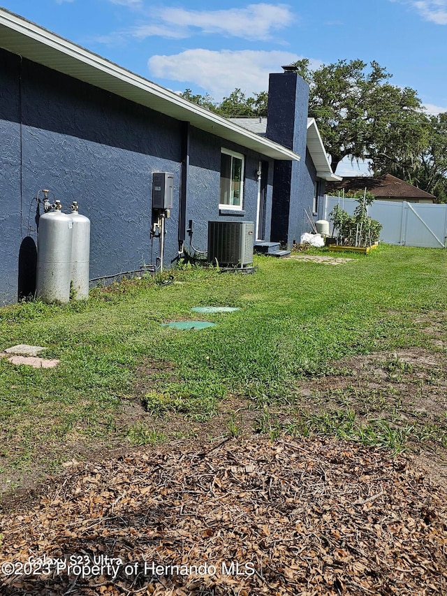 rear view of property with central AC unit and a yard