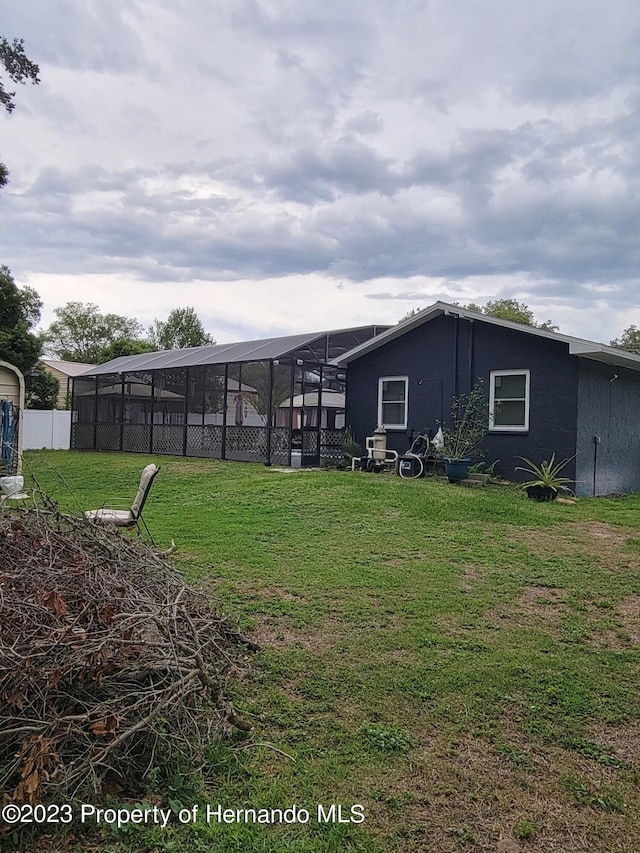 back of house featuring a lawn and a lanai