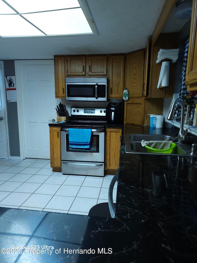 kitchen with appliances with stainless steel finishes, sink, and light tile patterned floors