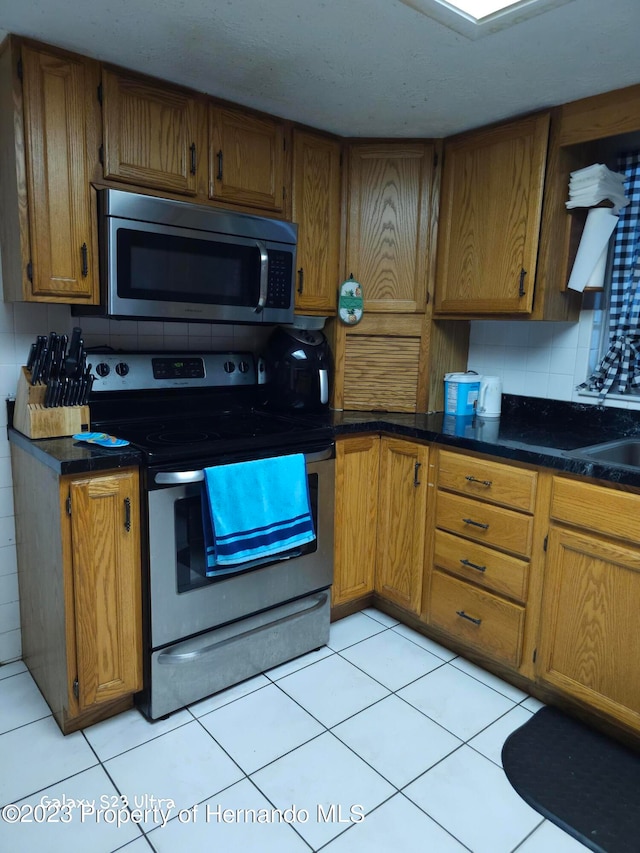 kitchen featuring appliances with stainless steel finishes, light tile patterned floors, and backsplash