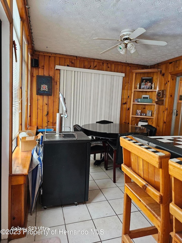 kitchen featuring wood walls, a textured ceiling, and light tile patterned floors