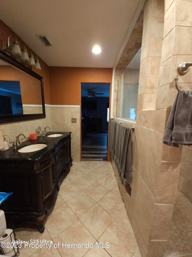 bathroom with ceiling fan, vanity, crown molding, tile patterned floors, and tile walls