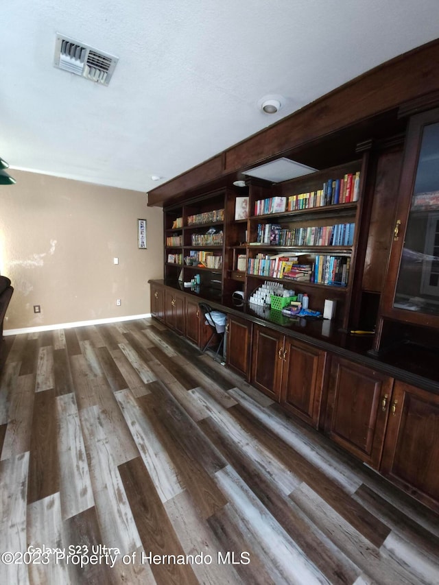 unfurnished office featuring dark hardwood / wood-style flooring and built in desk