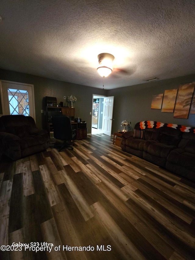 living room featuring a textured ceiling and dark hardwood / wood-style flooring