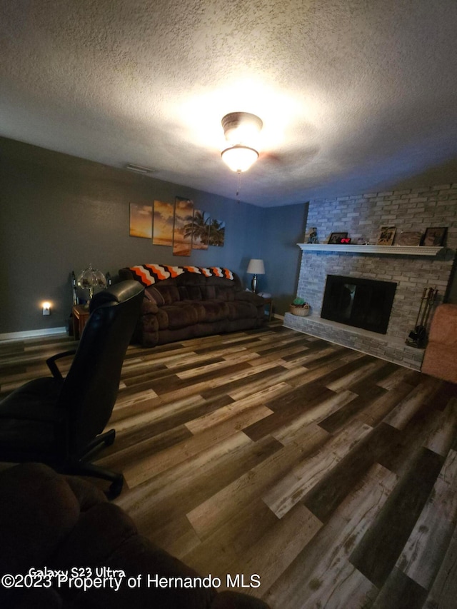 bedroom featuring a brick fireplace, hardwood / wood-style floors, and a textured ceiling