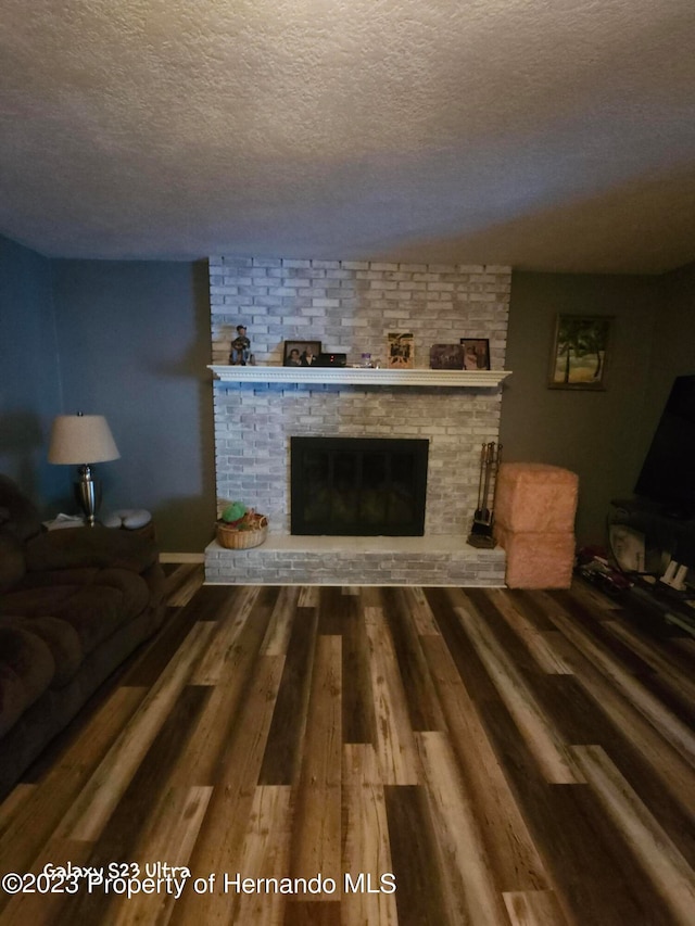 living room with hardwood / wood-style flooring, a fireplace, and a textured ceiling