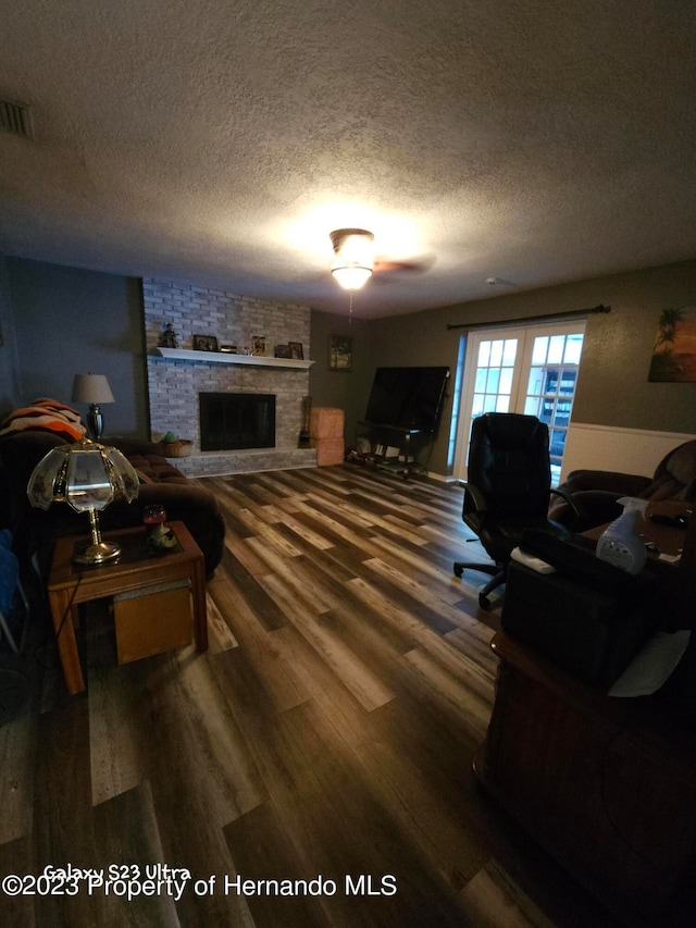 living room with a fireplace, wood-type flooring, and a textured ceiling