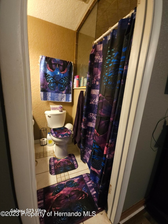 bathroom featuring curtained shower, tile patterned floors, toilet, and a textured ceiling