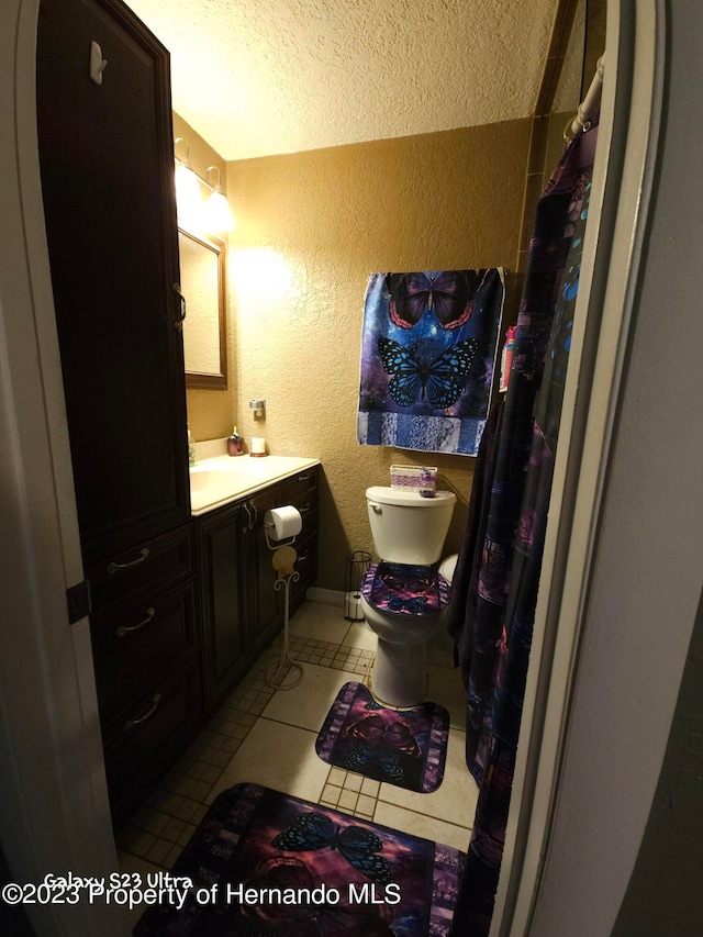 bathroom featuring tile patterned flooring, vanity, a textured ceiling, and toilet