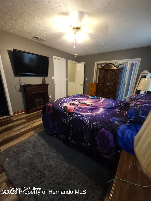 bedroom with a textured ceiling, hardwood / wood-style flooring, and ceiling fan