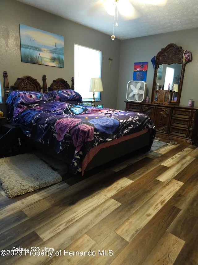 bedroom featuring hardwood / wood-style flooring, ceiling fan, and a textured ceiling