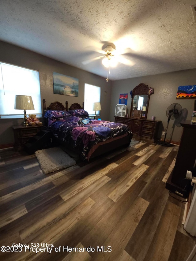 bedroom with dark wood-type flooring, ceiling fan, and a textured ceiling